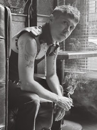 a man with tattoos sitting on a chair